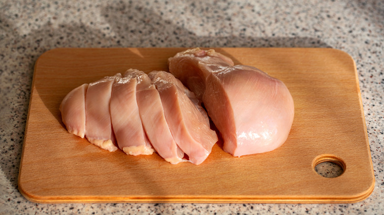 sliced raw chicken breast on a cutting board