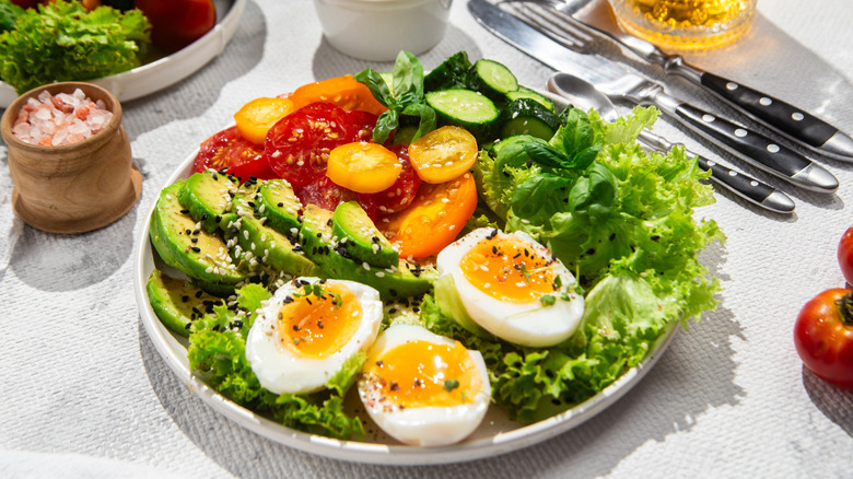 a fresh salad with boiled eggs, tomato, and avocado
