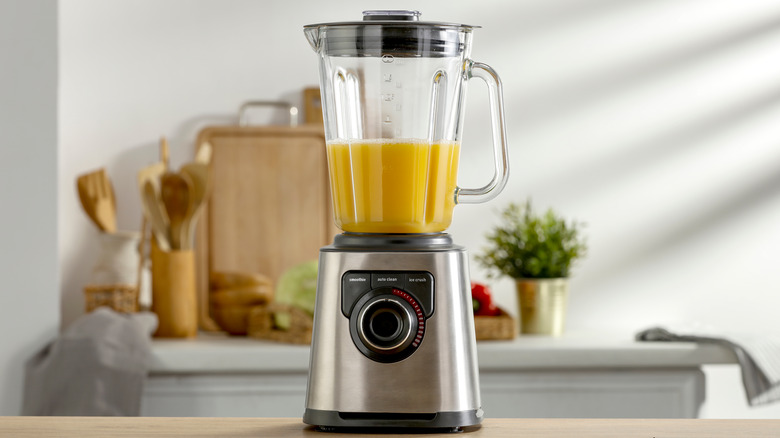 Blender with yellow drink on counter