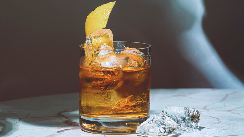 a bourbon cocktail over ice with lemon peel garnish