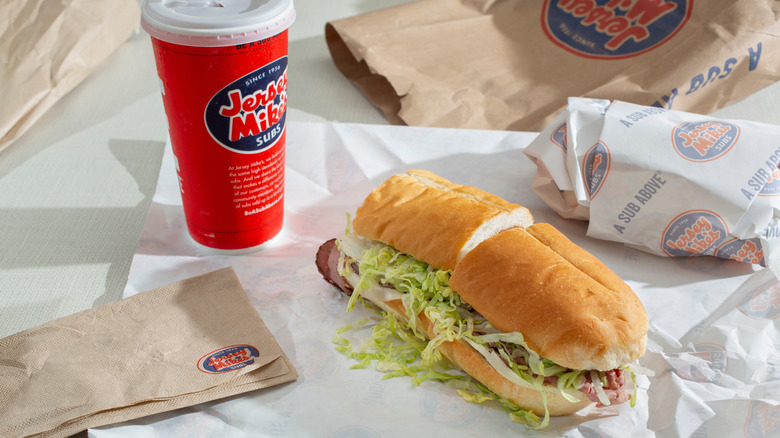 A Jersey Mike's sub sitting beside a drink and napkins