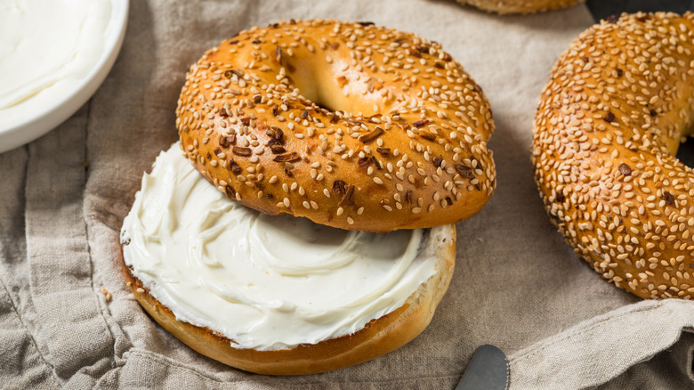Sliced bagel topped with seeds, filled with a thick spread of cream cheese.