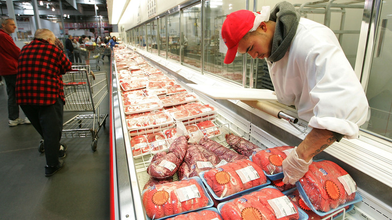 Costco employee arranging a meat display
