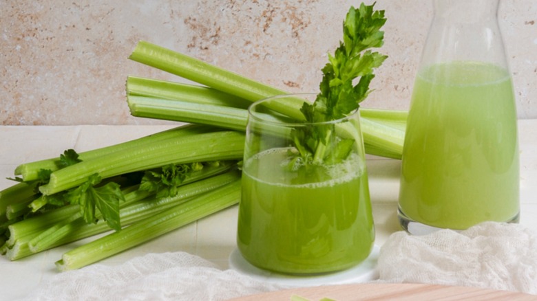 Jar and glass filled with celery juice beside celery stalks