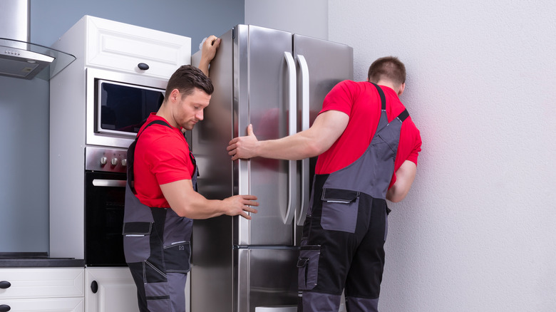 Professionals installing a refrigerator