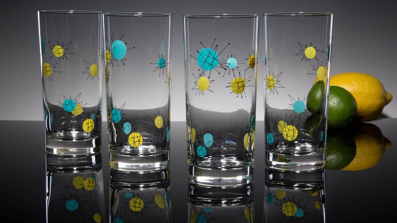 a set of glasses with atomic designs on them. A lemon and lime sit in the background