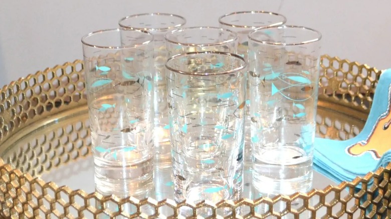 A set of glasses with an atomic design printed on them sit on a mirrored tray