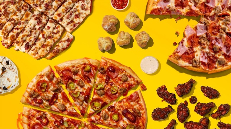 Pizza, wings, and ice cream in front of a yellow background