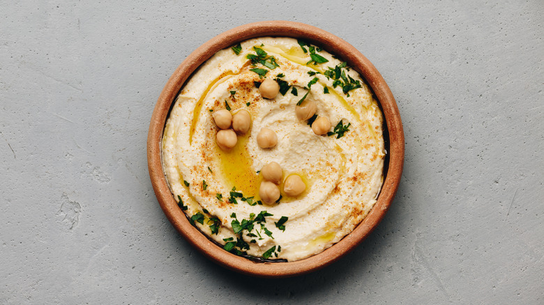 Hummus in a bowl with olive oil and garbanzo beans on top
