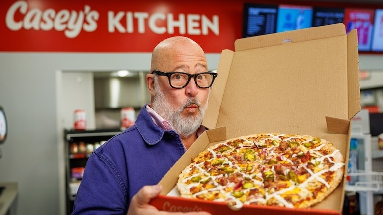 Andrew Zimmern holding up a pizza pie from Casey's General Stores