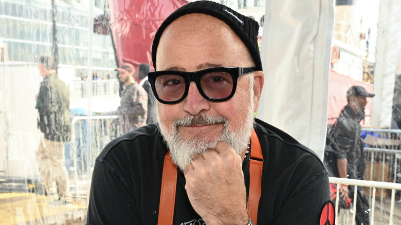 Andrew Zimmern smiles with dark shades and black beanie hat