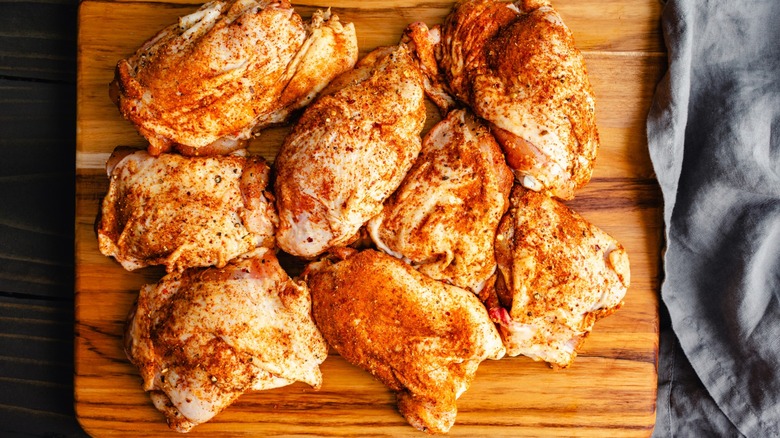 dry seasoned chicken thighs on a wooden board
