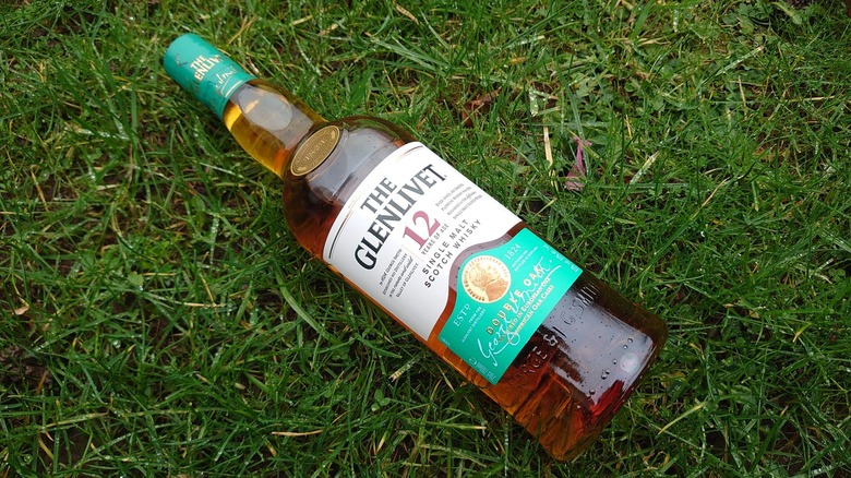 A bottle of The Glenlivet 12-year resting diagonally on the grass