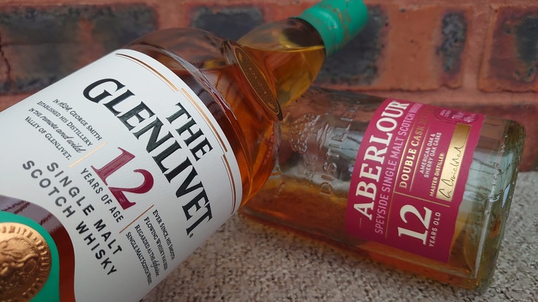 A close shot of a bottle of The Glenlivet 12-year resting on a bottle of Aberlour 12-year
