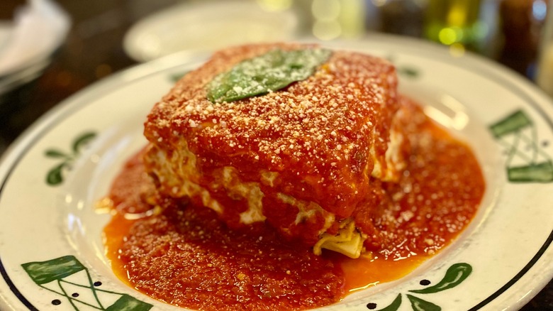 A slice of lasagne topped with red sauce and a basil leaf Mulberry Italian Ristorante