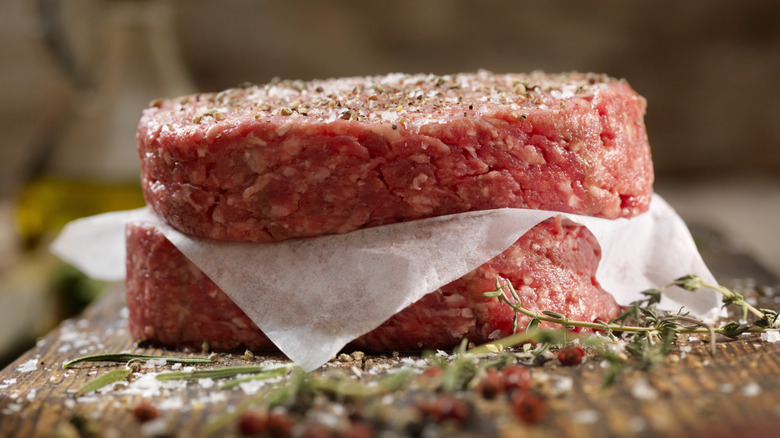 raw burger patties with seasoning