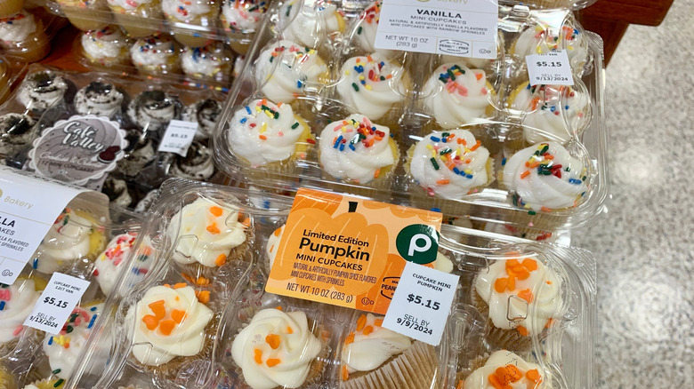 A container of Publix's pumpkin cupcakes beside a container of vanilla cupcakes