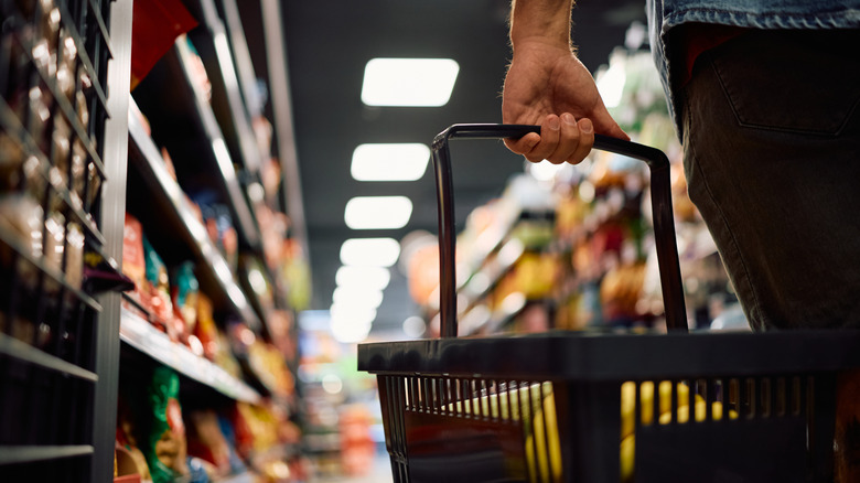 Man carrying basket through grocery store