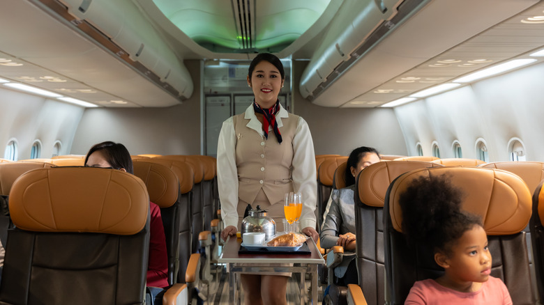 Flight attendant with drink cart.