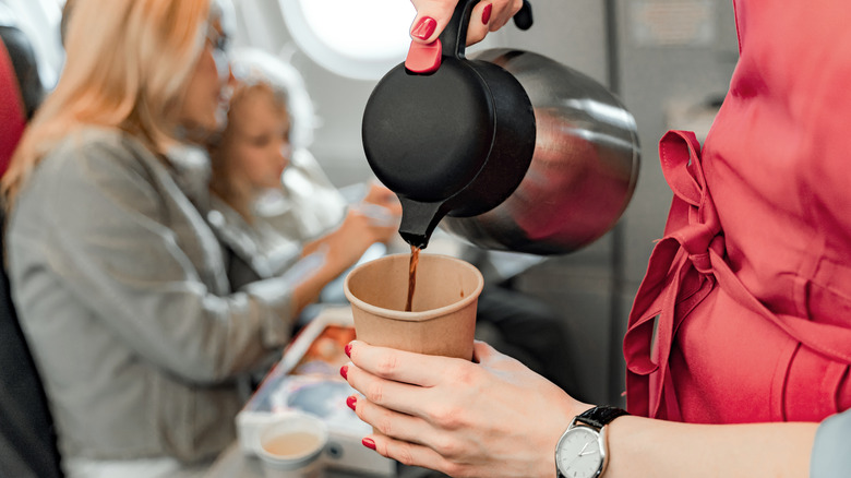 Flight attendant pouring coffee cup.