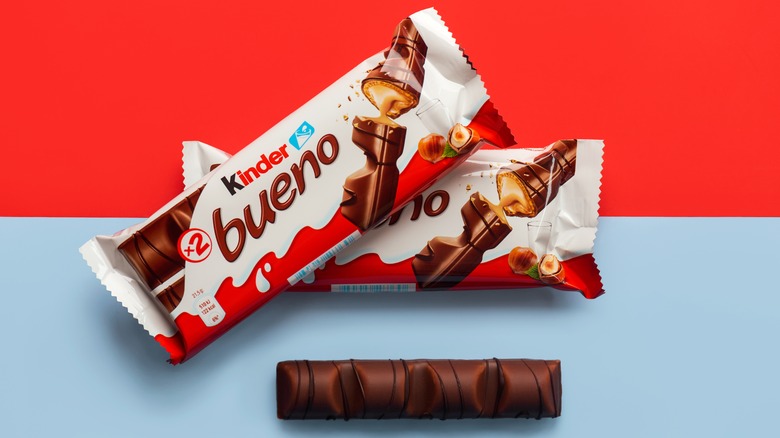Two packages of Kinder Bueno candy bars loosely stacked on top of one another above a single opened chocolate bar