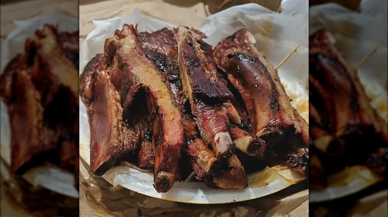 Smoked pork ribs on a paper plate with paper