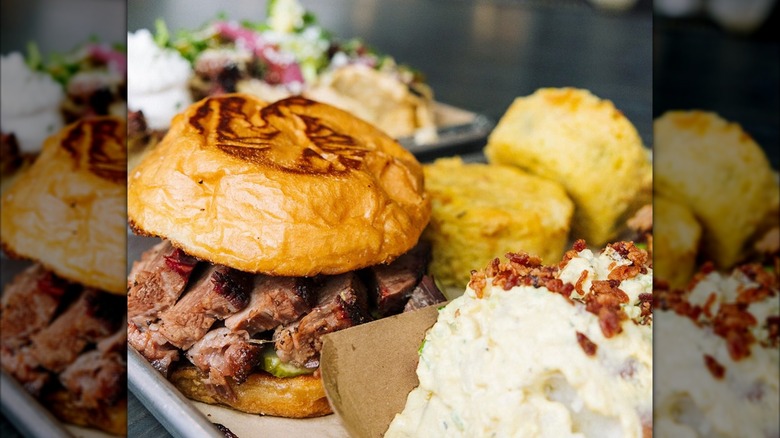 Sliced brisket sandwich with potato salad and cornbread