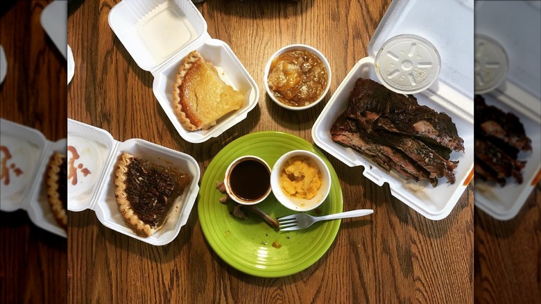 BBQ with sides and slices of pie on a wooden table