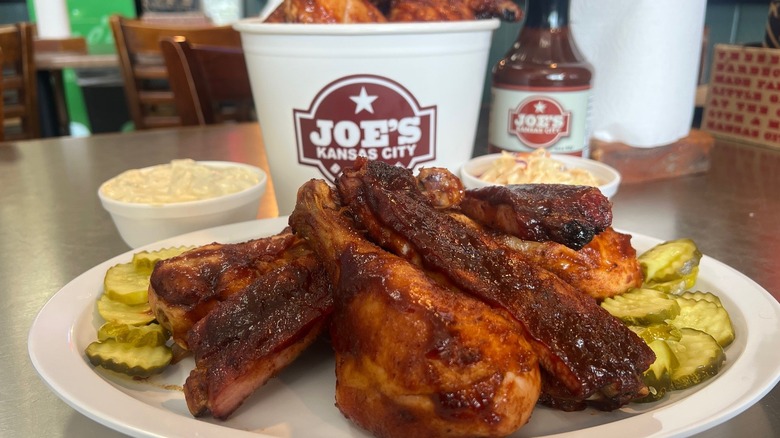 Plate of BBQ chicken and ribs with pickles and sides