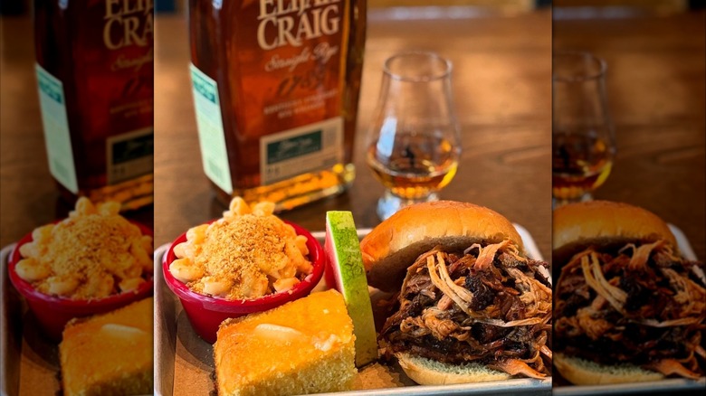 Pulled pork sandwich with mac and cheese, cornbread, and a bottle and glass of Elijah Craig whiskey