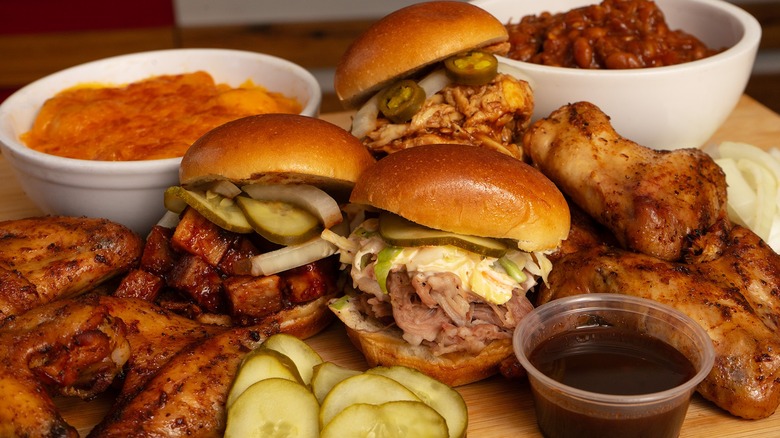 Platter with three BBQ sandwiches, chicken, pickles, and sides