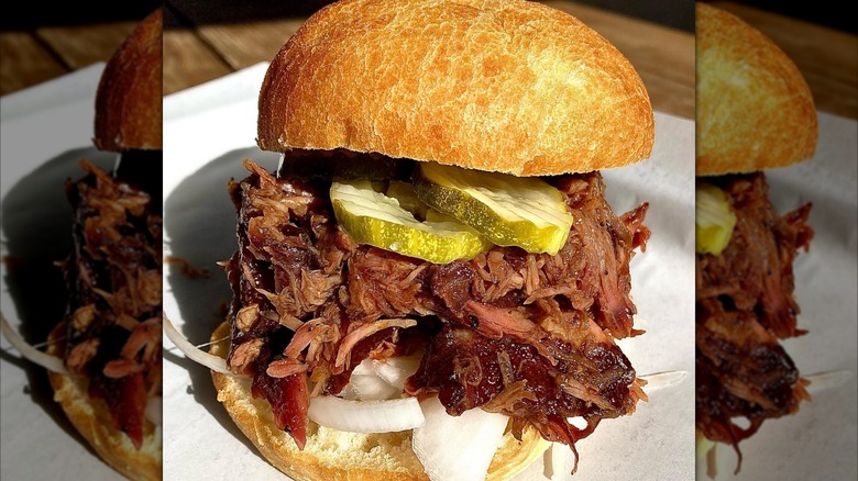 Pulled pork and rib sandwich with pickles and onions
