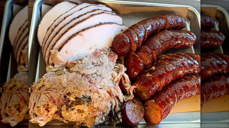 Smoked turkey, pulled pork, and sliced sausages on a tray