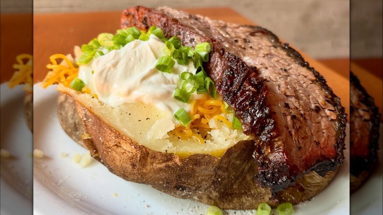 Baked potato with onions, cheese, sour cream, and a slice of brisket