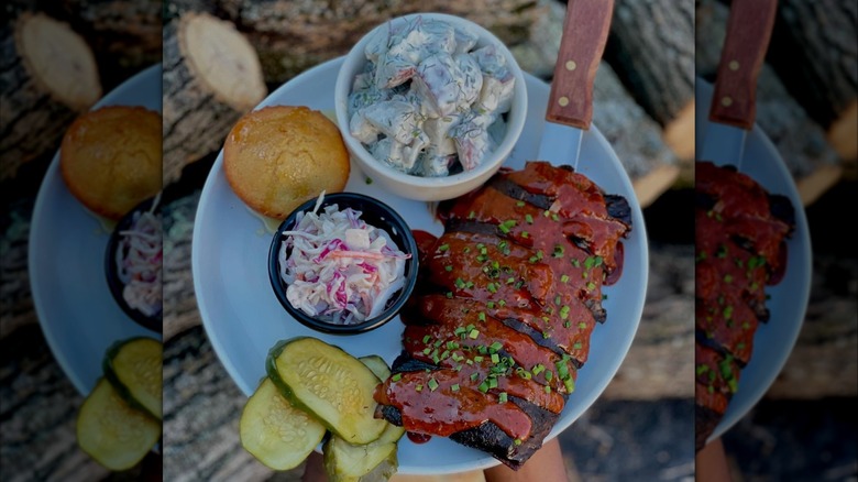 Plate of ribs, slaw, potato salad, pickles, and cornbread