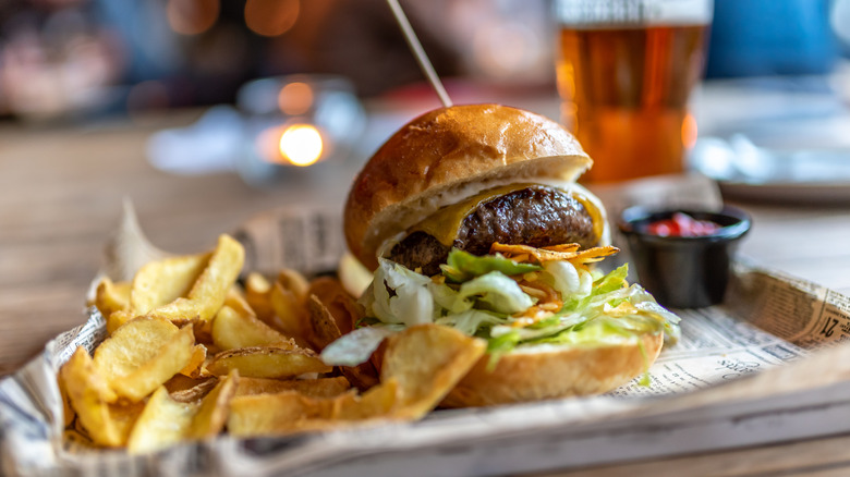 burger and french fries with cup of beer behinnd