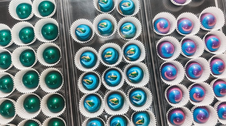 Overhead view of iridescent, aurora-inspired chocolates, individually wrapped in display cases