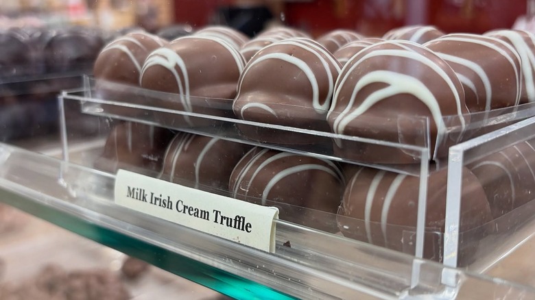Several milk Irish cream truffles on display in glass case