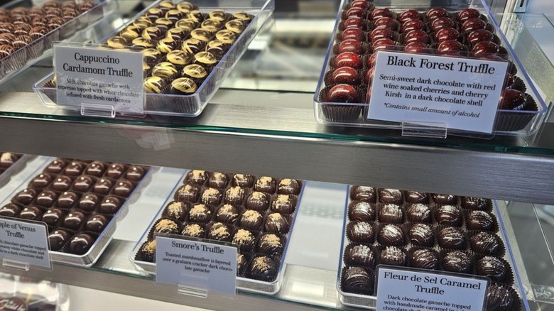 Truffles with flavors like Black Forest and Cappuccino Cardamom in glass display case