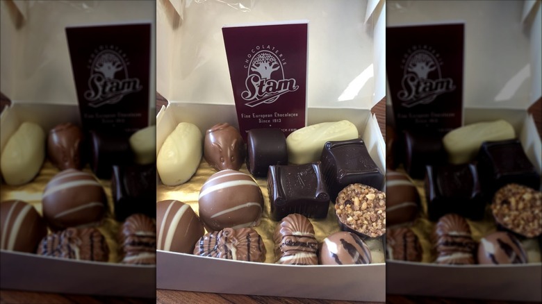Open box of chocolate confections alongside Chocolaterie Stam business card