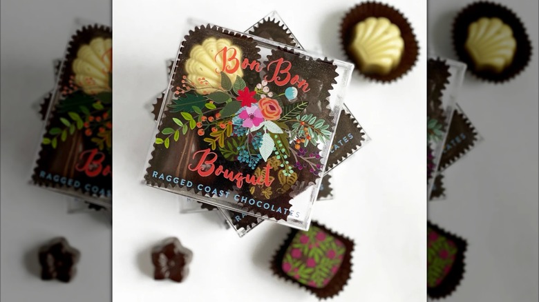 Overhead view of several boxes of chocolates stacked, with individual pieces scattered around