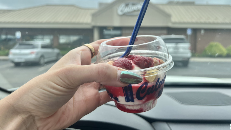 Person holding a small cup of custard from Culver's in their car