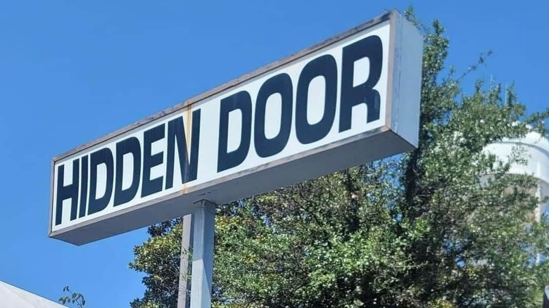 Won-out sign of Hidden Door with tree