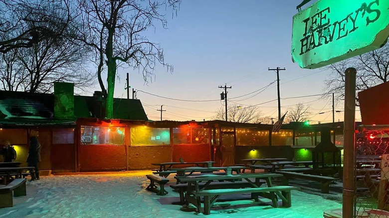 Snow-covered patio with Lee Harvey's sign and picnic tables