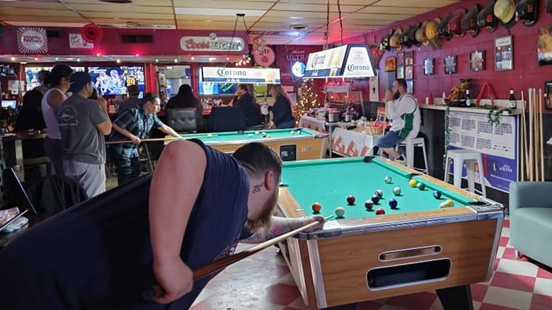 Pool tables with customers and lit beer signs at Willie's Lounge