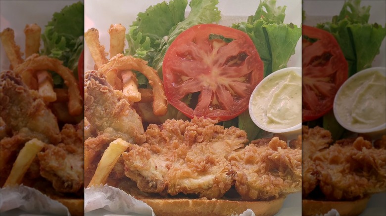Open faced fish sandwich with fries, tomato, lettuce, tartar sauce