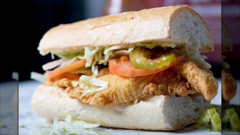 Fish sandwich on hoagie roll with tomatoes and pickles