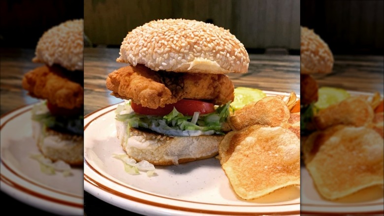 Fried fish sandwich on bun next to chips at CBG's