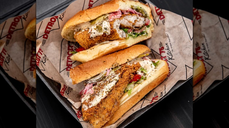 Two halves of fish sandwich on hoagie roll in paper-lined box