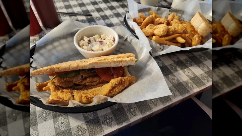 Catfish po'boy next to coleslaw in basket, fried shrimp and fries behind